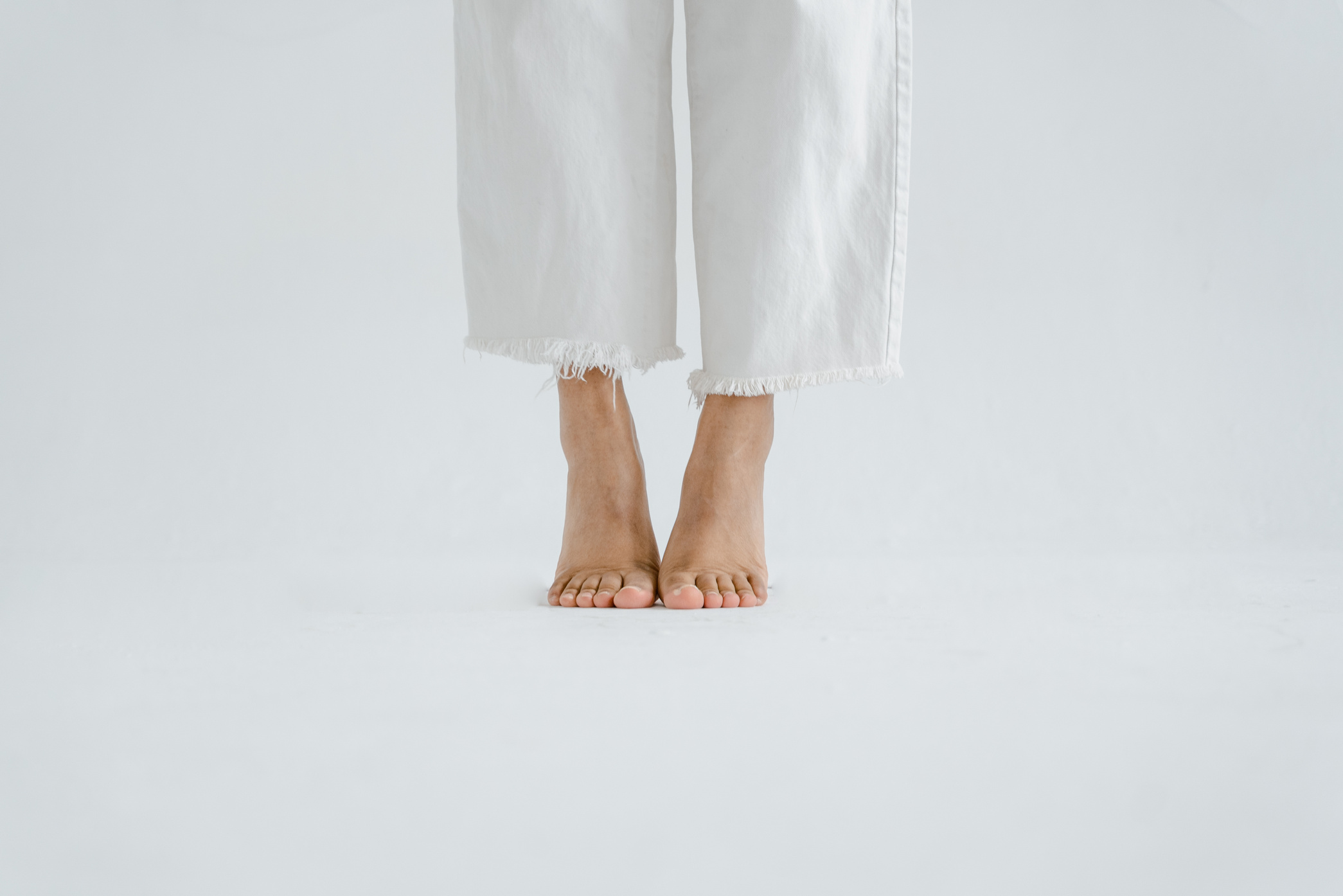 A Barefooted Person Wearing White Pants Tiptoeing